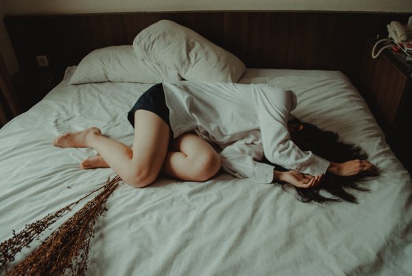 ベッドに横たわり落ち込む女性